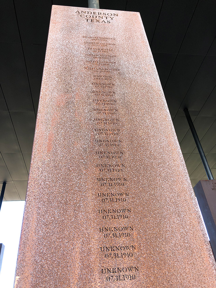 Looking up at a six-foot Corten steel monument for Anderson County Texas listing multiple unknown persons lynched on several dates.