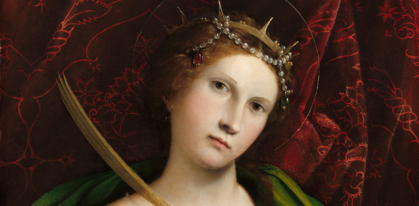 A painting of Saint Catherine with a halo, wearing a pink silk dress with a green wrap around her with yellow highlights, and a crimson velvet curtain in the background.