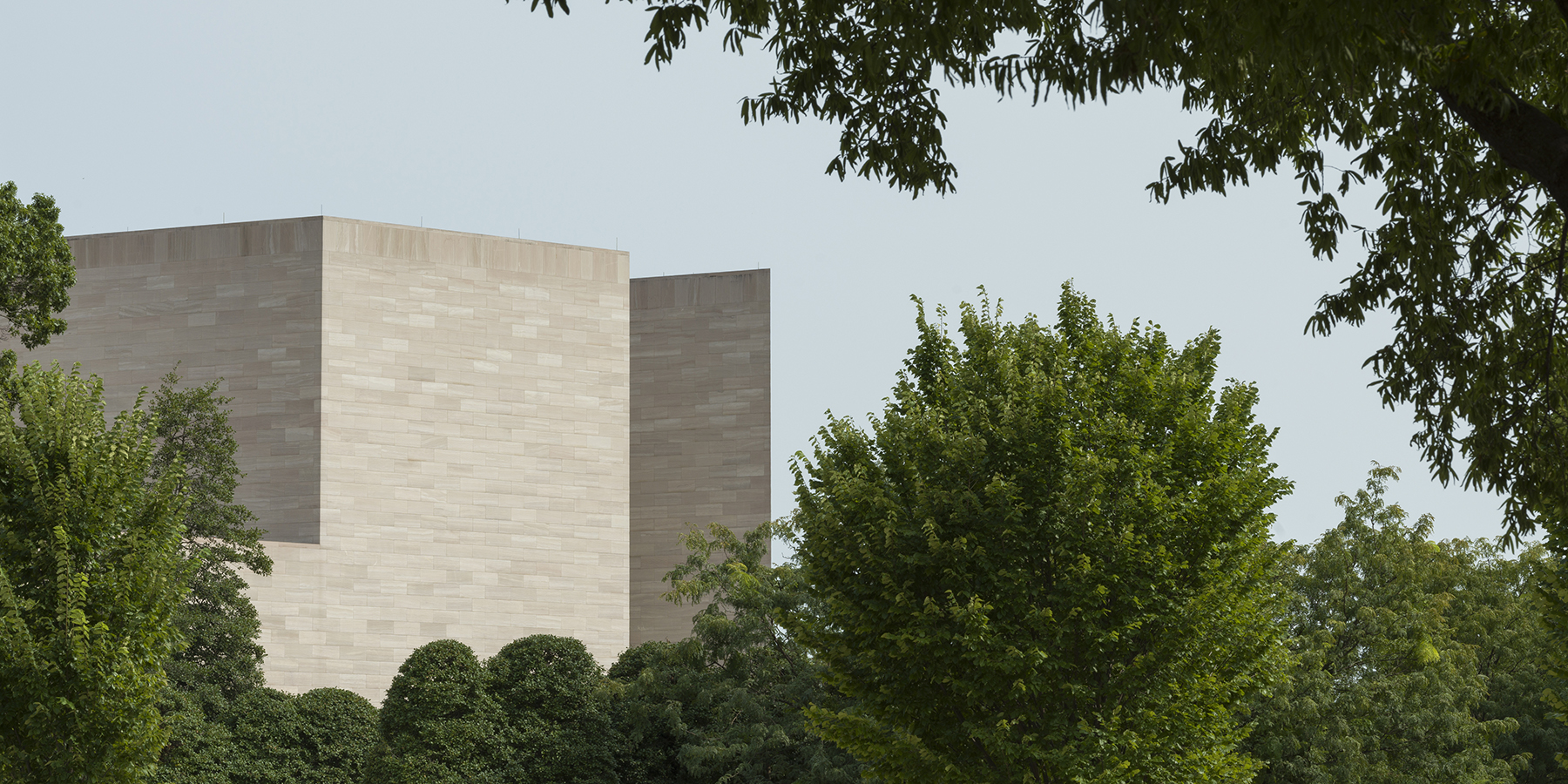 View of the top of the East Building tower, with green trees on each side