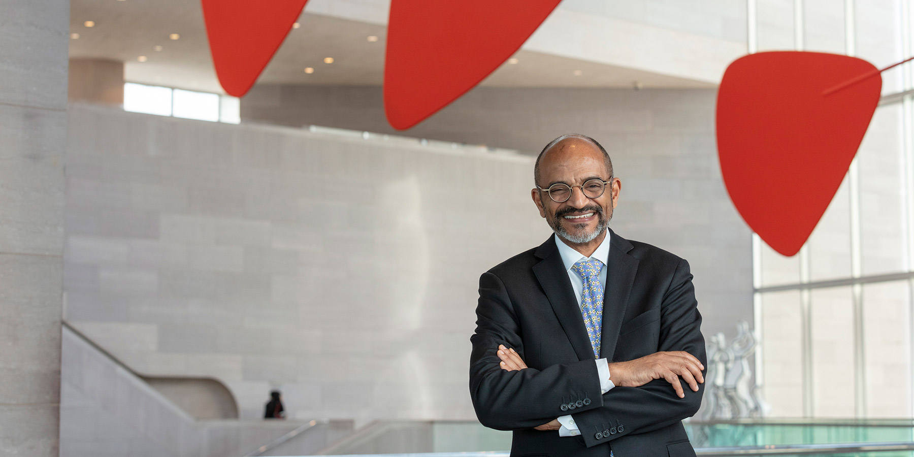 A woman walking from right to left through a gallery of the National Gallery's East Building. Three abstract paintings are hanging on the wall in the background.